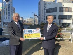岡田一般社団法人千葉南青色申告会長より根本千葉県タクシー協会市原支部副支部長へ確定申告PRマグネット授与（ＪＲ五井駅西口ロータリーにて）